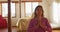 Relaxed mixed race woman practicing yoga, sitting meditating and smiling in sunny cottage bedroom