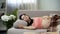 Relaxed pregnant lady sweetly sleeping on sofa, hugging her tummy with baby
