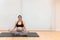 A relaxed pregnant woman sitting on a mat doing yoga at home with copy space