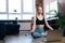 Relaxed redhead young woman with closed eyes meditating sitting in lotus position on yoga mat