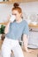 Relaxed redhead young woman holding cup of hot coffee while standing in kitchen room.