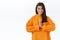 Relaxed and relieved happy smiling gorgeous woman in orange hoodie, press hands together in pray, say namaste, practice