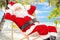 Relaxed Santa Claus sitting on a chair, on a beach