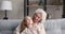 Relaxed senior grandma hugging talking with child granddaughter at home