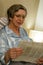 Relaxed smiling mature woman reading newspaper