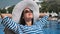 Relaxed smiling woman in sunglasses and white hat sunbathing near swimming pool medium close-up