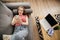 Relaxed smiling young young woman texting on cellphone lying on sofa at home. Top view