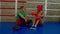 Relaxed sporty black woman boxer and coach sitting on boxing ring after training