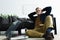 relaxed stylish man in eyeglasses sitting with hands behind head and listening music with vinyl record player