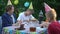 Relaxed teenagers and children eating tasty chocolate cake with soda water celebrating birthday on backyard picnic