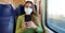 Relaxed train passenger using smartphone app during travel commute wearing protective face mask. Panoramic banner of people