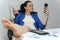 Relaxed and winning business woman sitting with her legs on desk and looking at her shoes