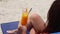 Relaxed woman drinking fresh orange cocktail sitting in sunbed on sandy beach.