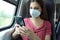 Relaxed woman with KN95 FFP2 face mask using smart phone app. Train passenger with protective mask traveling sitting in business