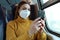 Relaxed woman with KN95 FFP2 face mask using smart phone app. Train passenger with protective mask traveling sitting in business