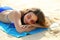 Relaxed woman lying down on sand during summer vacation. Beautiful girl lying down under the sun tanning in a tropical beach.