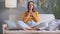 Relaxed woman meditating in her living room at home sitting in lotus pose with crossed legs and with hands together praying