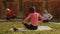 Relaxed woman meditating in lotus pose on yoga carpet in autumn forest. Yoga woman relaxing by meditation music on