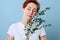 Relaxed woman with short ginger hair holding eucalyptus branch