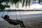 Relaxed woman sits in a hammock overlooking the Indian Ocean in the Maldvies at sunset