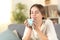 Relaxed woman smelling coffee on a couch at home