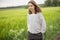 Relaxed woman standing in green field and enjoys calm nature