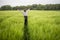 Relaxed woman standing in green field and enjoys calm nature