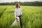 Relaxed woman standing in green field and enjoys calm nature