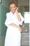 Relaxed woman standing in white bathrobe