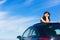 Relaxed woman on summer vacation leaning out sunroof