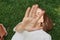 Relaxed woman wearing white t shirt lying on green grass in park outstretching hand covering her face with palm enjoying free tome