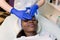 Relaxed Young African Woman Receiving Forehead Massage In Spa. Woman massagist in blue rubber gloves performing facial