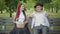 Relaxed young Caucasian couple sitting on bench in summer park and chatting. Portrait of positive elegant man and woman