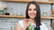 Relaxed young housewife in apron dancing drinking fresh healthy cocktail posing at kitchen