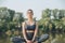 Relaxed young woman doing yoga outdoors in a beautiful spot on a riverside