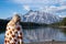 Relaxed young woman draped in a pumpkin blanket enjoys the view at Two Jack Lake in Banff National Park