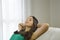 Relaxed young woman taking a nap on sofa. Smiling young woman with green tank top relaxing on a sofa at home sitting on a sofa in