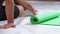 Relaxing athletic man sitting on the floor next to unwinded roll mat, cleaning place after sports. Sportive man doing