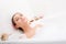 Relaxing attractive young woman lying in the bath with foam, enjoying spa relaxation treatment eyes closed