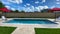 A relaxing backyard swimming pool with red umbrellas