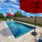 A relaxing backyard swimming pool with red umbrellas