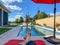 A relaxing backyard swimming pool with red umbrellas