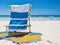 Relaxing beach scene with blue chair, sandy shore, and serene horizon