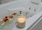 A relaxing candle and rose petals in a bathroom
