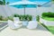 Relaxing inviting view of luxury outdoor backyard furniture with blue great umbrella and comfortable white beautiful chairs