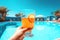 Relaxing by the pool from the first person, with a refreshing orange drink in hand. sky background. Generative AI