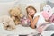 Relaxing before sleep. Girl enjoy evening time with toys. Kid lay bed with toys pillow blanket background. Girl child