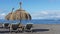 Relaxing spot on the pebble beach of Playa de la Enramada with two thatched umbrellas and four chaise lounges
