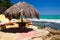 Relaxing terrace with thatched reed umbrella, yellow bank and view on turquoise water