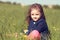 Relaxing thinking cute kid girl sitting in green grass in sunny